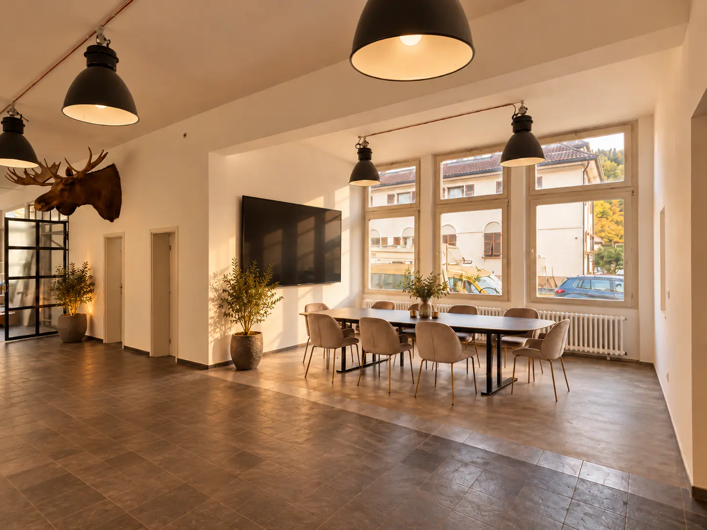 Meetingraum mit Konferenztisch, großem Bildschirm und hohen Fenstern